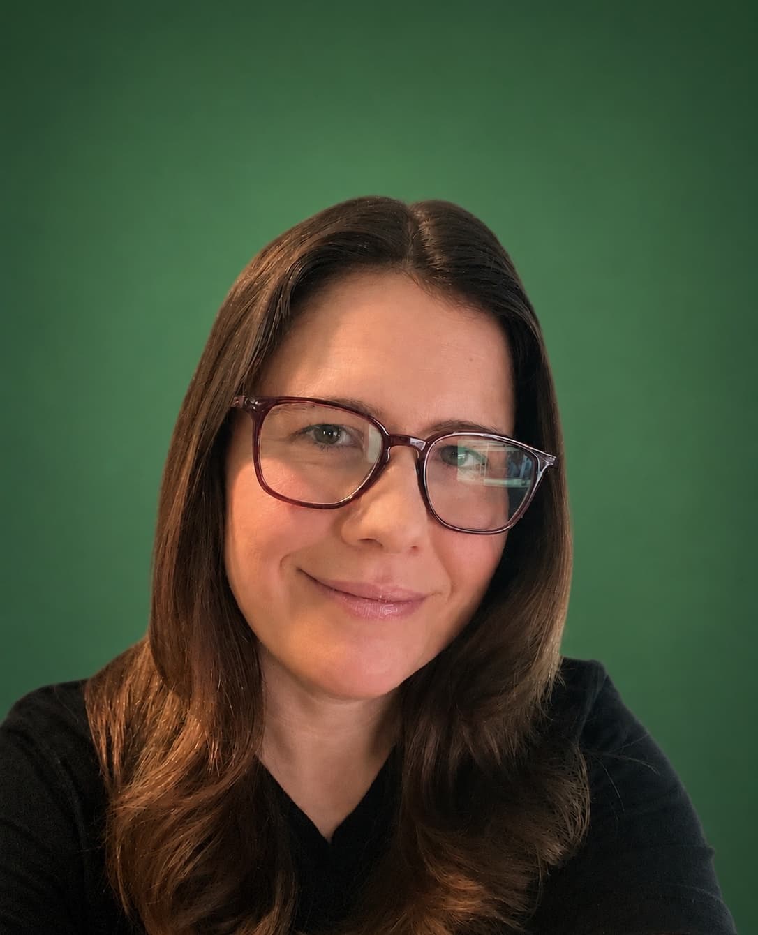 Headshot of Jen Ross, founder of Mercury Jane, wearing glasses and a black top against a verde green backdrop